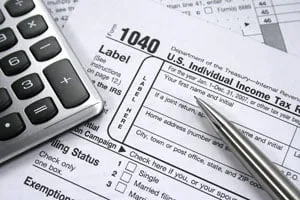 Formulario 1040 del IRS con una calculadora y una pluma, listos para la preparación de impuestos